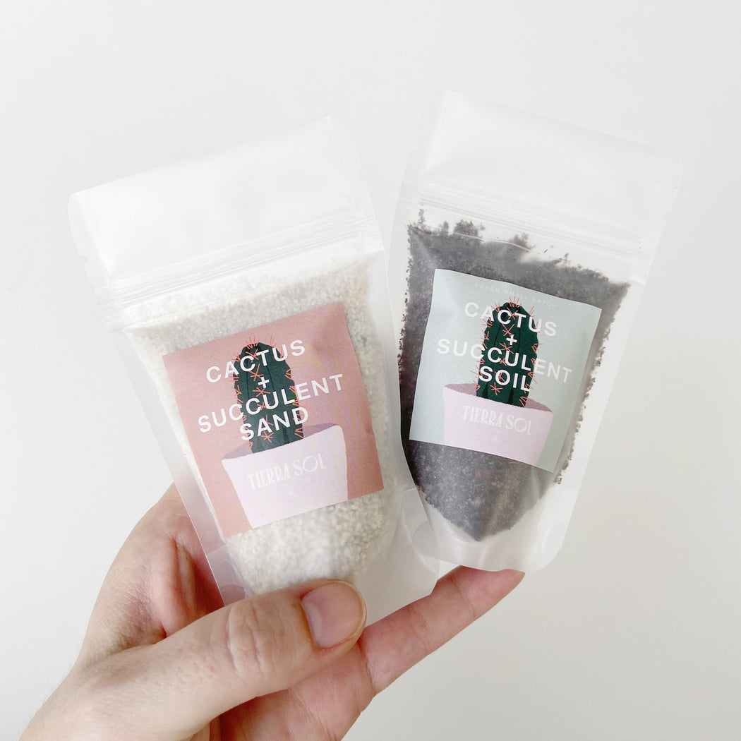 A Hand holding bags of Cactus and Succulent  Soil and Sand that fits in a 4 in pot